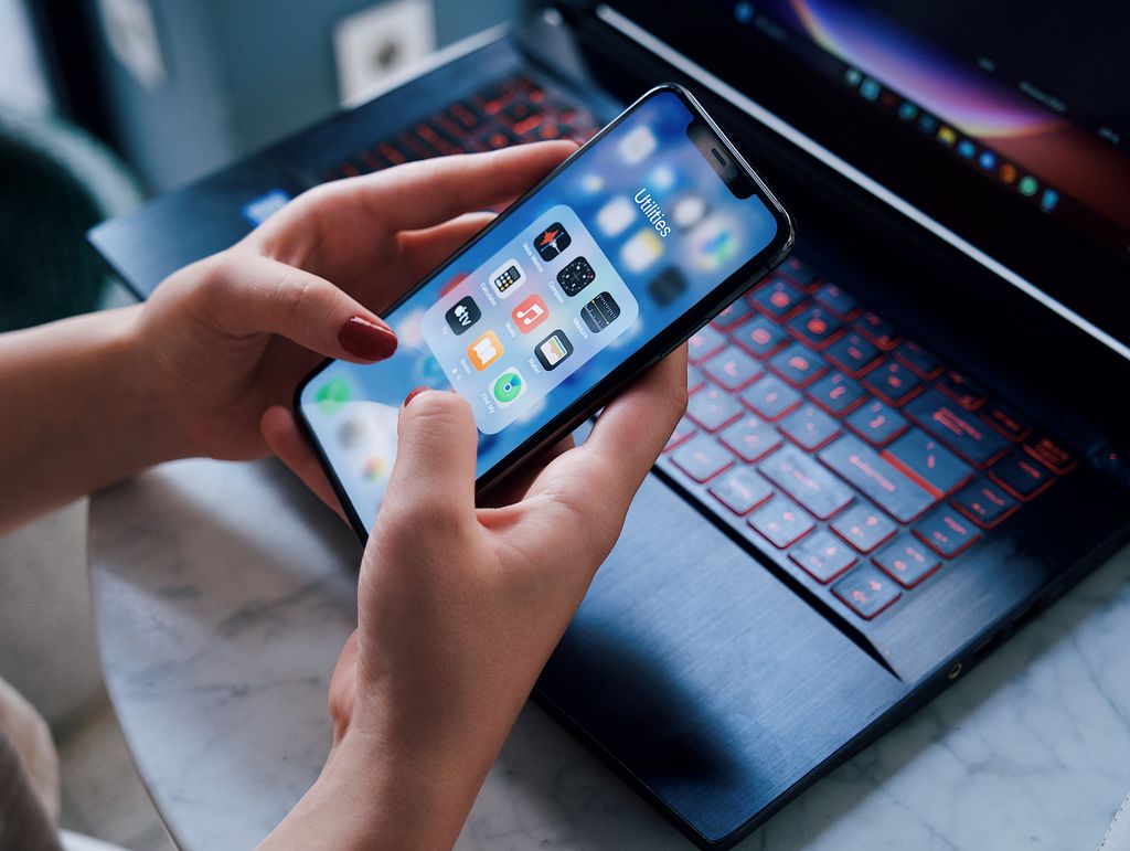 Femme utilisant un smartphone et un ordinateur pour effectuer des recherches ou des appels